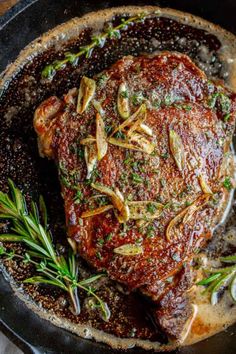 a piece of meat in a skillet with herbs and seasoning on it, ready to be cooked