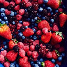 berries, raspberries and blueberries are arranged in a large bowl on the table