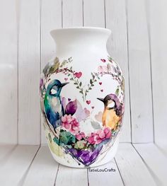 a vase with two birds painted on it's sides and flowers in the middle