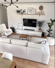 a living room filled with white furniture and a flat screen tv mounted on the wall