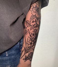 a woman's arm with flowers and leaves on it