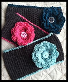 three crocheted purses are laying on a quilted surface, one has a flower and the other has a button