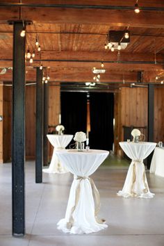 an empty room with tables and chairs covered in white tablecloths, decorated with flower centerpieces