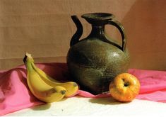 two bananas and one apple sit next to an old jug on a pink tablecloth