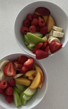 two white bowls filled with sliced fruit on top of a marble countertop next to each other