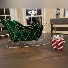 a green sleigh sitting on top of a wooden table next to a present box