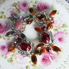 an elaborately decorated plate with flowers and jewels on it's edges, in the shape of a flower