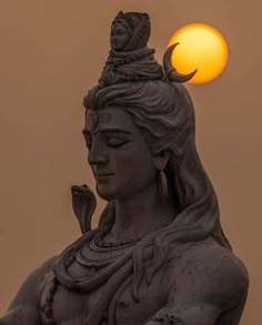 the sun is setting behind a statue of a woman with a snake on her shoulder