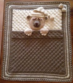 a crocheted blanket with a teddy bear in the pocket on top of it