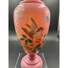 a pink vase with a bird painted on it's side and flowers in the bottom