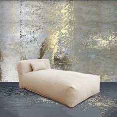 a couch sitting on top of a floor next to a wall with gold paint all over it