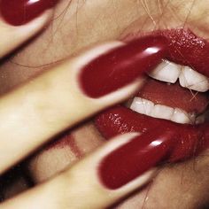 a woman with red lipstick on her face and hands holding it up to the camera