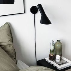 a black lamp on a nightstand next to a bed