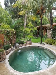 an outdoor swimming pool surrounded by trees and plants in a backyard area with stone steps leading up to it