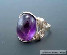 a large purple stone sitting on top of a metal wire wrapped around an adjustable ring