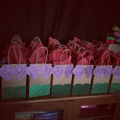 several bags are lined up on the shelf in front of a bookcase with purple and green paper