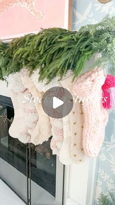 the stockings are hanging on the mantle in front of the fireplace and decorated with greenery