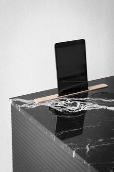 an open laptop computer sitting on top of a black marble desk with a wooden tabletop