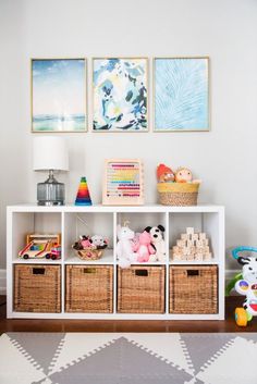 a white shelf with baskets and stuffed animals on it in a child's room