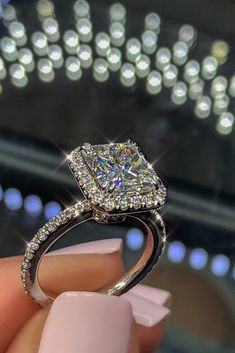 a woman's hand holding an engagement ring with diamonds on it and the center stone is