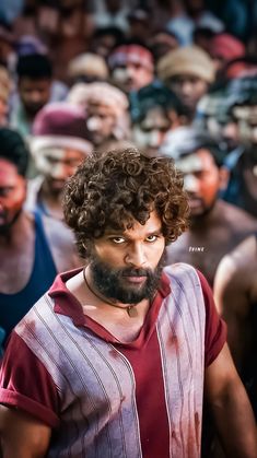 a man with curly hair and beard standing in front of a crowd