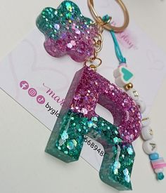 a key chain with the letter e on it and charms attached to it's sides