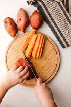 a person cutting up carrots on top of a wooden cutting board