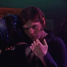 a woman with her arm around another woman's shoulder in a dark room,