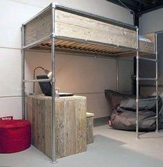 a loft bed sitting in the middle of a room next to a red trash can