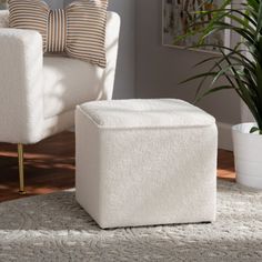 a living room with a white chair and ottoman next to a large potted plant