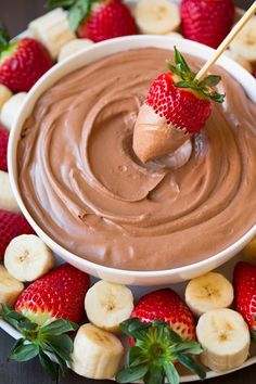 a chocolate dip surrounded by sliced bananas and strawberries