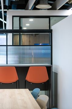 two orange chairs sitting next to each other on top of a wooden table in an office