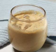 a glass filled with liquid sitting on top of a blue and white table cloth next to a