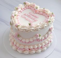 a heart shaped birthday cake with pink and white frosting