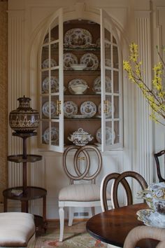 a dining room with china cabinet, chairs and vases on the table in front of it