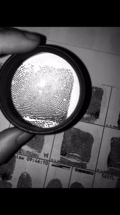 a hand holding a magnifying glass over a fingerprint