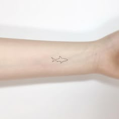 a small shark tattoo on the arm