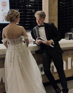 a man in a tuxedo standing next to a woman