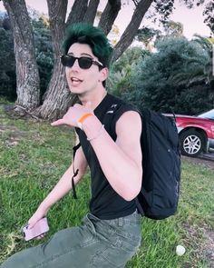 a man with green hair sitting on the grass