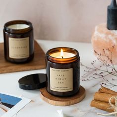 two candles sitting on top of a table next to cinnamon sticks and other items in front of them