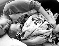 a young child sleeping on top of a bed next to an adult and baby doll