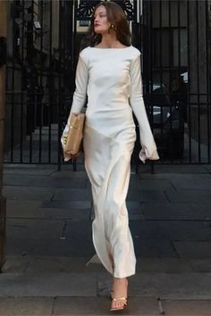 a woman in a white dress is walking down the street