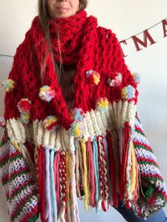 a woman wearing a red knitted scarf with tassels and pom poms