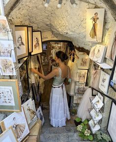 a woman is looking at pictures on display in a room with stone walls and ceilings