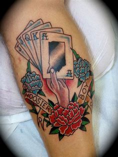 a woman's arm with tattoos on it and four playing cards in the middle