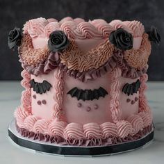 a three tiered cake decorated with pink icing and black flowers