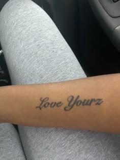 a woman's arm with the words love yourz tattooed on her left arm