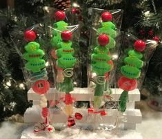 some green and red stuffed animals in plastic bags on a white table next to a christmas tree