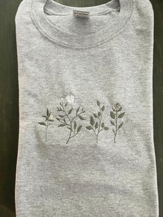 a gray t - shirt with flowers embroidered on it