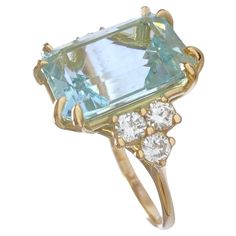 an aqua and white topazte ring with three diamonds on the sides, set in yellow gold